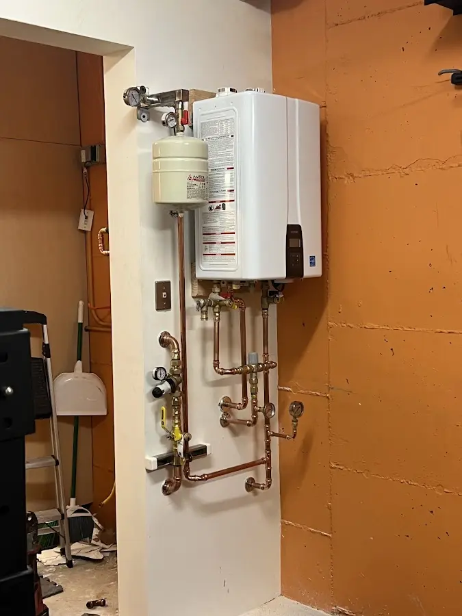 Plumbing technician inspecting water heater connections in Four Corners